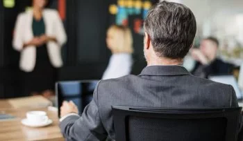 Zdjęcie przedstawia osobę prezentującą przed niewielką grupą